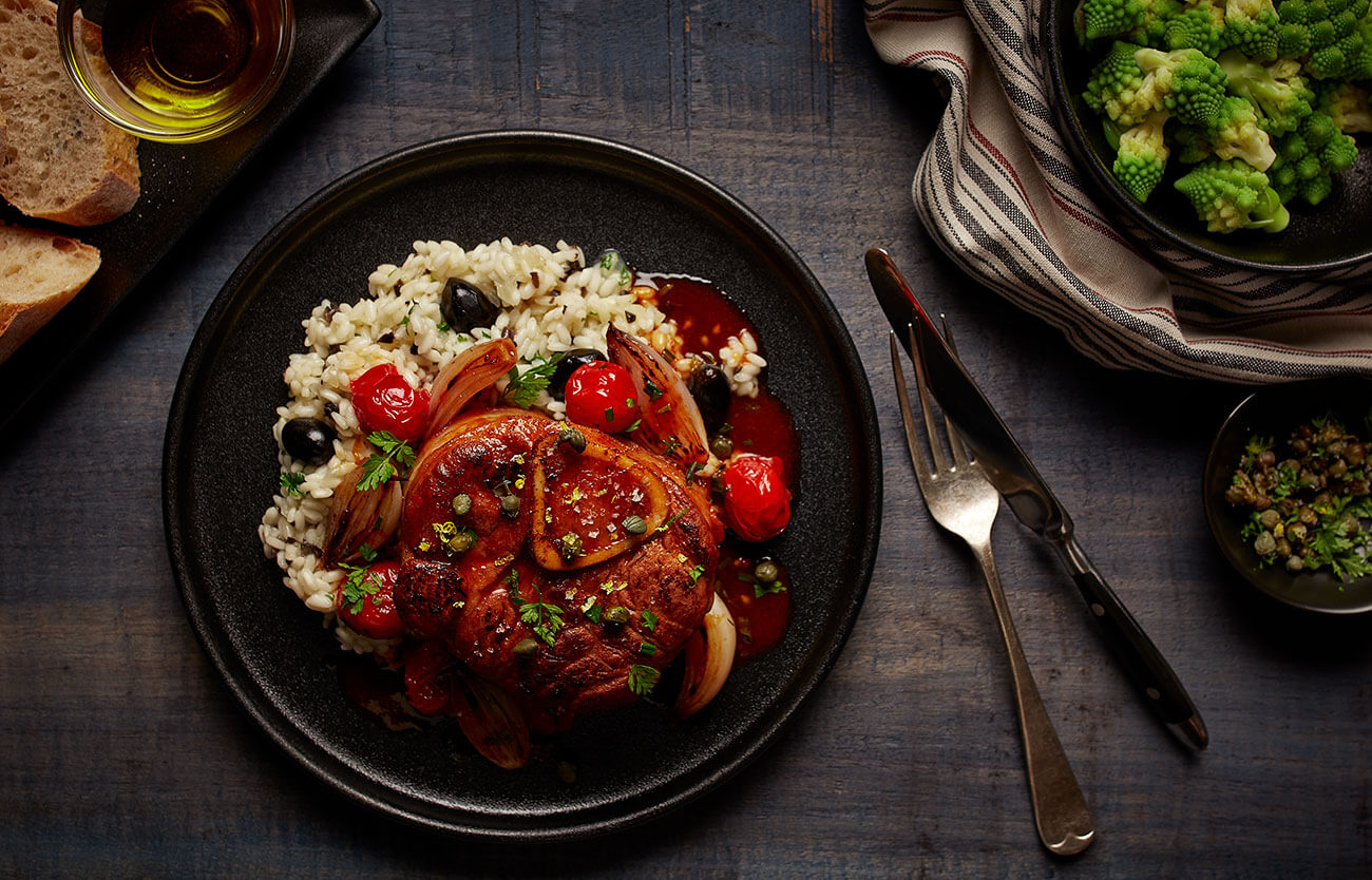 Osso buco with shallots, Milanino tomatoes, salted capers and Italian herbs, served with risotto and olive tapenade